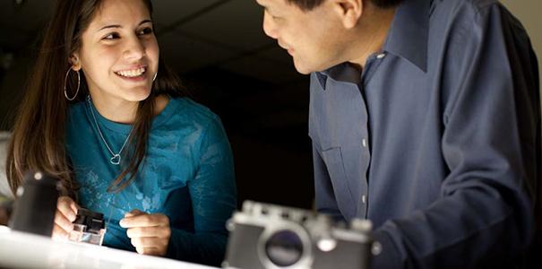 Professor talking with smiling female college photography student